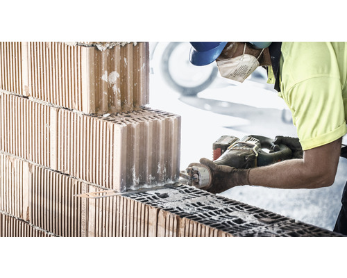 Un ouvrier coupe une brique avec une scie alligator