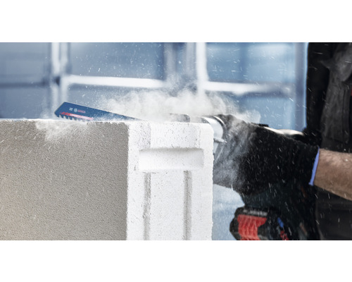 Eine Säbelsäge schneidet einen Porenbetonstein.