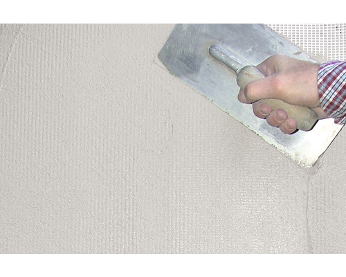 Une personne lisse du plâtre avec une lisseuse sur un mur.