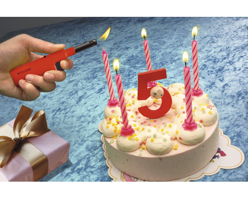 Une main allume des bougies sur un gâteau d''anniversaire avec un briquet.