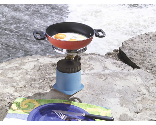 Campingkocher mit Bratpfanne und Spiegeleiern auf einem Felsen neben einem Wasserfall