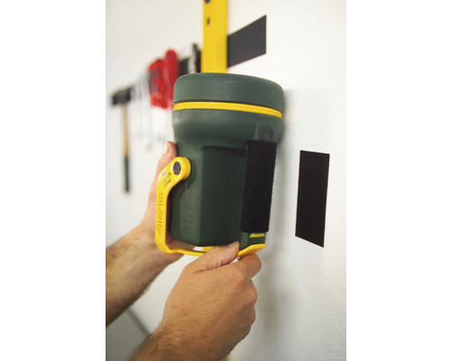 Hand hält Nivelliergerät mit Klettverschluss an Wand.