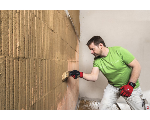Un homme applique du plâtre sur un mur en briques