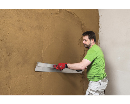 Mann glättet Putz mit einer Glättkelle an der Wand