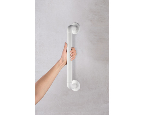 Une main tient une barre d''appui blanche fixée au mur