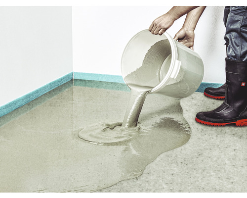 Une personne verse de l''enduit de nivellement d''un seau sur un sol.