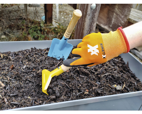 Szene mit einer Hand in Gartenhandschuhen, einem gelben Unkrautstecher und einer blauen Schaufel in einem Pflanzgefäß mit Erde.