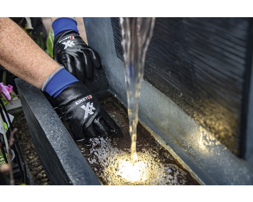 Person mit Arbeitshandschuhen reguliert den Wasserfluss eines Wasserfalls