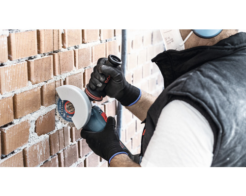 Artisan coupant un mur de briques avec une meuleuse d''angle