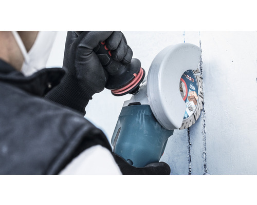 Une personne utilise une meuleuse d''angle sur un mur.