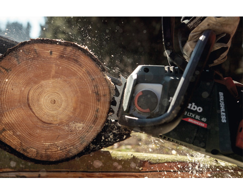 Une tronçonneuse coupe une bûche.