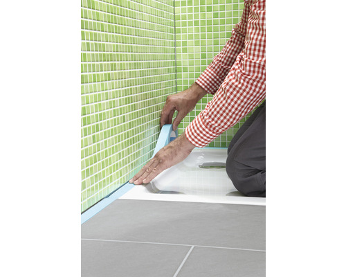 Un artisan scelle un receveur de douche avec du ruban d''étanchéité dans la salle de bain.