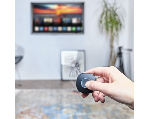 Eine Hand bedient eine drahtlose Fernbedienung in einem Wohnzimmer