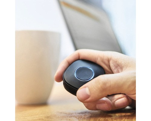 Une main tient une télécommande noire.