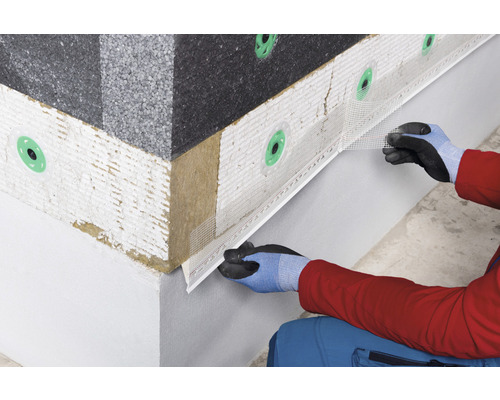 Detailaufnahme einer Person, die ein Fassadendämmsystem mit Armierungsgewebe an einer Hauswand installiert.