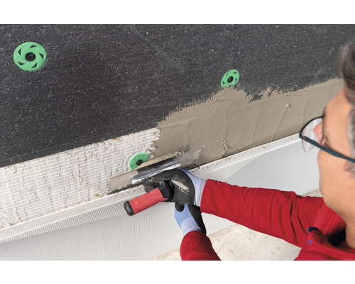 Handwerker trägt Putz auf eine Wand mit Dämmstoffplatten auf