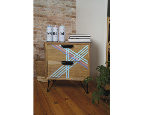 Commode en bois avec motif géométrique, aérosols et livres