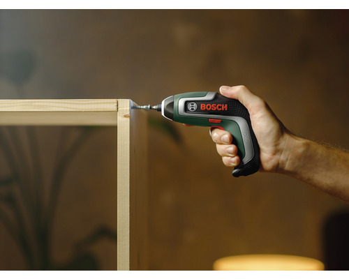Une personne visse une vis dans une planche de bois avec un tournevis sans fil Bosch.