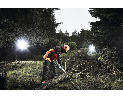 Bûcheron coupant une bûche avec une tronçonneuse dans la forêt