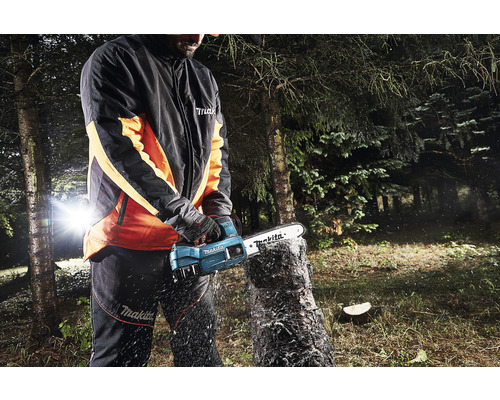 Une personne scie une souche d''arbre avec une tronçonneuse à batterie Makita.