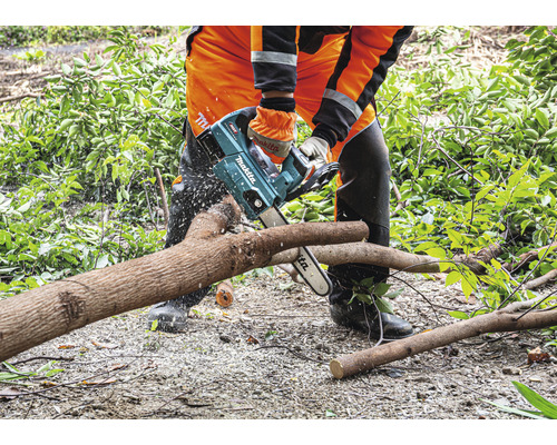 Une personne coupe un tronc d''arbre avec une tronçonneuse Makita.