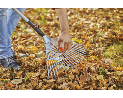 Laub rechen mit einem Laubbesen auf einem Rasen