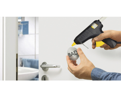 Heissklebepistole beim Anbringen eines Objekts an einer Tür