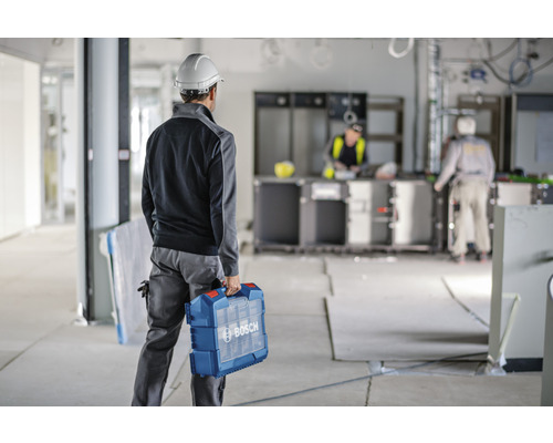 Un ouvrier du bâtiment avec une boîte à outils de la marque Bosch sur un chantier.