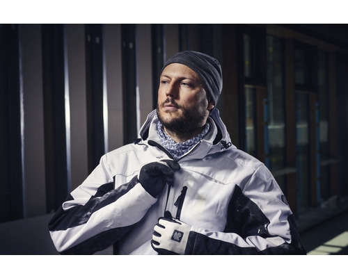 Mann mit Mütze, Handschuhen und Arbeitsjacke