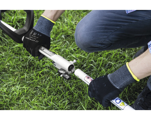 Montage d''une débroussailleuse par une personne portant des gants de travail dans le jardin