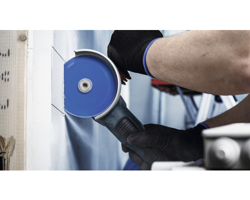 Eine Person schneidet mit einem Winkelschleifer eine Trockenbauwand.