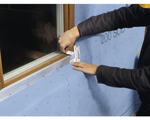 Application de ruban d''étanchéité sur un cadre de fenêtre sur un chantier.