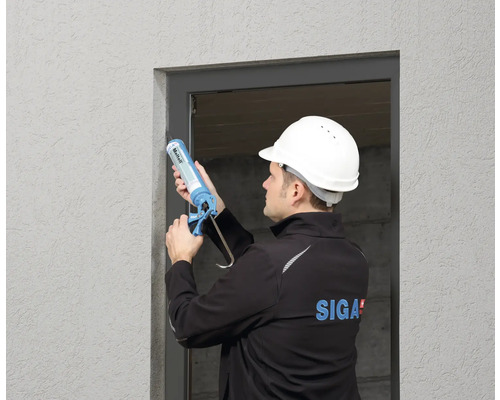 Un ouvrier scelle une ouverture de fenêtre avec du mastic