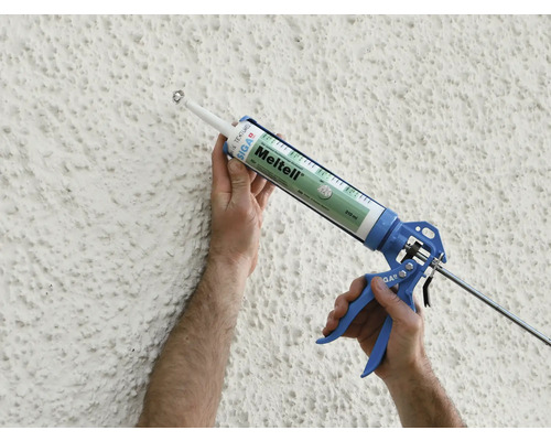 Photo extérieure d''une personne appliquant du mastic sur un mur avec un pistolet à cartouche