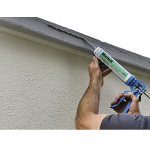 Application de mastic d''étanchéité avec un pistolet à cartouche sur un mur de maison