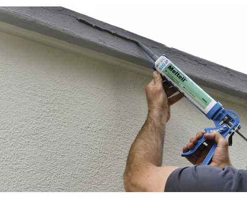 Application de mastic d''étanchéité avec un pistolet à cartouche sur un mur de maison