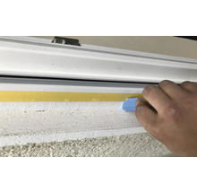 Vue extérieure d''une fenêtre avec un ruban d''étanchéité appliqué à l''aide d''un outil