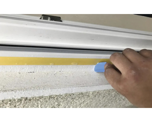 Vue extérieure d''une fenêtre avec un ruban d''étanchéité appliqué à l''aide d''un outil