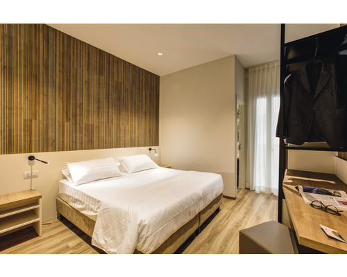 Helles Schlafzimmer mit Doppelbett, Holzwand und offenem Kleiderschrank