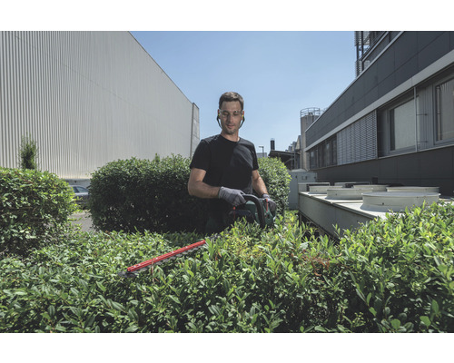 Un homme taille une haie avec un taille-haie