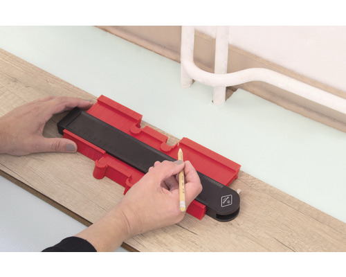 Une personne utilise une jauge de contour pour tracer sur un plancher en bois
