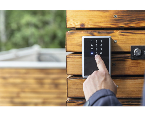 Une personne utilise un digicode sur un mur en bois