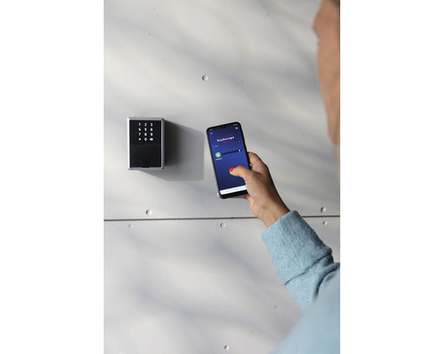 Une femme utilise une application sur smartphone pour faire fonctionner un dépôt de clés