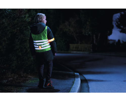 Kind mit reflektierender Sicherheitsweste und Armband bei Dunkelheit