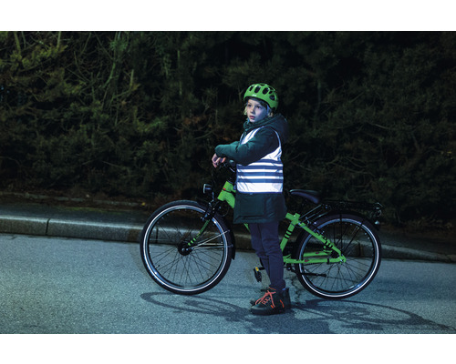 Enfant avec casque de vélo et gilet de sécurité à côté d''un vélo sur la route