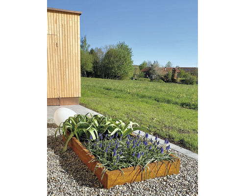 Jardinière en métal avec plantes fleuries et boule décorative dans le jardin