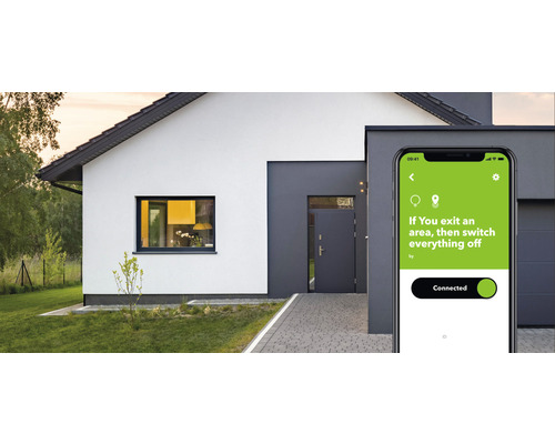 Smartphone avec application Smart Home devant une maison.