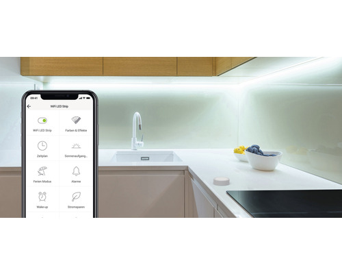 Smartphone avec une application pour contrôler les bandes LED dans une cuisine moderne.