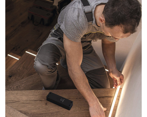 Artisan installant un éclairage d''escalier à LED dans une cage d''escalier.