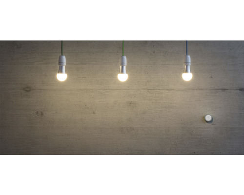 Trois ampoules LED suspendues devant un mur en béton.